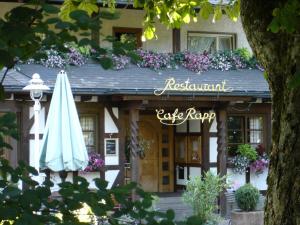 a building with an umbrella and flowers on it at Hotel Restaurant Café Rapp in Königsfeld im Schwarzwald