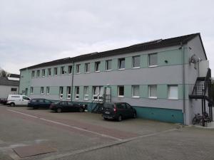 ein weißes Gebäude mit Autos auf einem Parkplatz in der Unterkunft Expresszimmervermietung in Duisburg