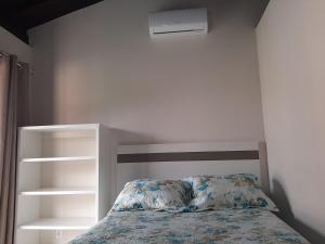 um quarto com uma cama e uma estante de livros em Pousada Barra da Lagoa em Florianópolis