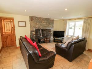 sala de estar con 2 sofás de cuero y chimenea en Penllyn, en Llanfairpwllgwyngyll