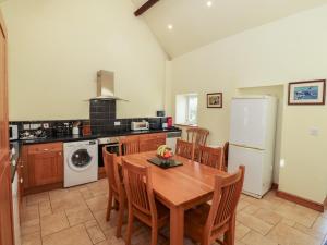 cocina con mesa, sillas y nevera en Penllyn, en Llanfairpwllgwyngyll