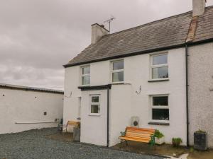 a white house with a bench in front of it at Bron Gadair in Llanfairpwllgwyngyll