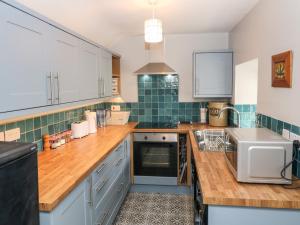a kitchen with wooden counter tops and green tiles at Penmaen House in Caernarfon