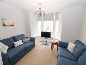 a living room with two blue couches and a tv at Penmaen House in Caernarfon