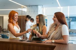 three women sitting at a bar with glasses of wine at Mercure St. Julian's Malta in St. Julianʼs +171 photos