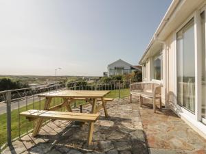 a patio with a table and benches on a balcony at Gwel An Mor in Newquay