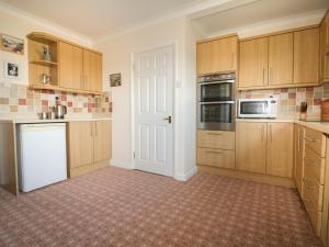 a kitchen with wooden cabinets and a white door at Gwel An Mor in Newquay
