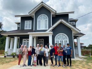 a group of people standing in front of a house at Shafickza Guesthouse in Kuala Terengganu