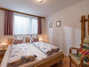 a bedroom with a bed and a window and a chair at Haus Laimbauer in Kirchdorf in Tirol