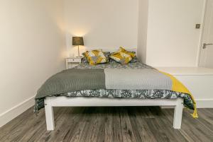 a bedroom with a bed with yellow and green pillows at Denby Lodge in Letchworth