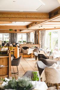 a dining room with tables and chairs and windows at Traumhotel Alpina Superior Adults Only Hotel in Gerlos