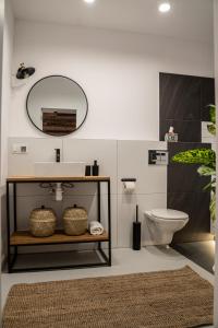 a bathroom with a toilet, sink and mirror at Folk by Anne Apartments & Rooms in Warsaw