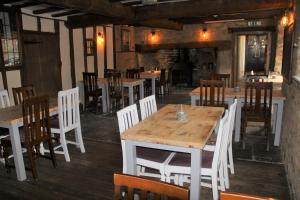 una sala da pranzo con tavoli e sedie bianchi di The George Inn a Lower Brailes