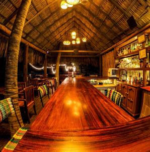 a large wooden table in a restaurant with a bar at Casa Lu Hotel Boutique in Mazunte