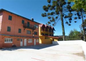 a large orange building with a tree in front of it at Chalés Vill'Agi in Campos do Jordão