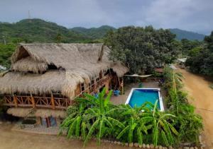 an aerial view of a house with a thatch roof at La Natura Hostel & Pool in Palomino