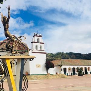 a building with a clock tower with a statue in front of it at Camino A La Villa Cucaita Hotel in Cucaita