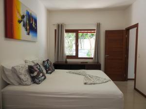 a bedroom with a large white bed with a window at Lovely Pipa in Pipa