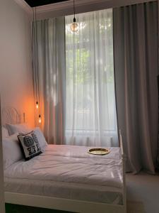 a bed with a white comforter on top of it at Folk by Anne Apartments & Rooms in Warsaw