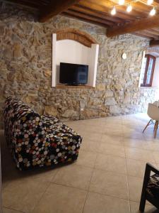 ein Wohnzimmer mit einem TV und einem Sofa in einer Steinmauer in der Unterkunft Casa Vanessa in Suvereto
