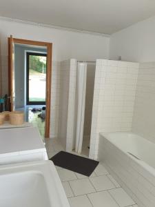 La salle de bains blanche est pourvue d'une baignoire et d'une douche. dans l'établissement La bergerie, maison spacieuse avec grand jardin, vue sur les Pyrénées, à Lourdes