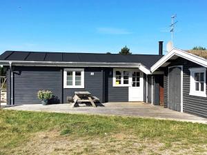 a black house with a picnic table in front of it at 6 person holiday home in R m in Lakolk