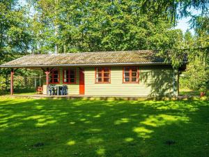 a small white house with red windows in a yard at 6 person holiday home in Toftlund-By Traum in Arrild