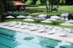 a pool with chairs and umbrellas next to a golf course at Hotel Avandaro Golf & Spa Resort in Valle de Bravo