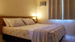 a bedroom with a bed with white sheets and a window at Vilamar Suítes in Aquiraz +15 photos