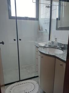 een badkamer met een douche, een wastafel en een spiegel bij Apartamento Enseada com varanda in Guarujá