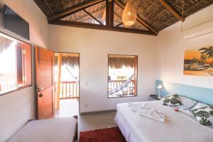 a bedroom with two beds and a door and windows at Pousada Aconchego da Pipa in Pipa