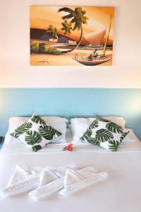 ein Bett mit Kissen und ein Bild von einem Strand in der Unterkunft Pousada Aconchego da Pipa in Pipa