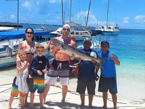 eine Gruppe von Menschen, die mit einem Fisch am Strand stehen in der Unterkunft Cande's Apartments in Isla Mujeres