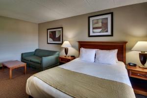 a hotel room with a bed and a chair at Best Western East Towne Suites in Madison +25 photos