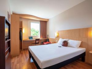 a hotel room with a large white bed and a desk at Ibis Hotel Plzeň in Pilsen