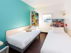 hotelF1 Avranches Baie Du Mont Saint Michel في Saint-Quentin-sur-le-Homme: سريرين في غرفة بجدران زرقاء