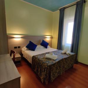 a hotel room with a bed with blue pillows and a window at Hotel Ducale in Favaro Veneto