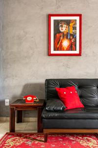 sala de estar con sofá de cuero negro y almohada roja en Vintage Apartments Florianópolis, en Florianópolis