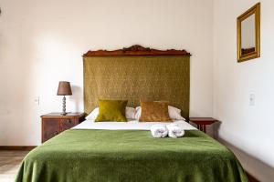 1 dormitorio con 1 cama verde y 2 toallas en Vintage Apartments Florianópolis, en Florianópolis
