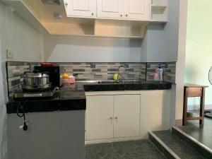 a kitchen with white cabinets and a sink at Beinte Singko de Marso Apartments in Candon