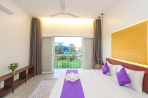 ein Schlafzimmer mit einem großen Bett mit lila Kissen in der Unterkunft Phan NaTa Apartment in Siem Reap