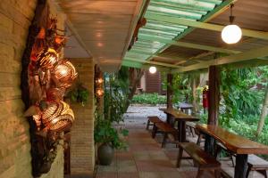 a restaurant with wooden tables and benches and plants at Baan Kitsada in Amphawa