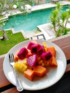 a white plate of fruit and vegetables on a table at Anyar Estate in Canggu