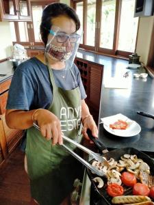 a woman in a kitchen preparing food on a grill at Anyar Estate in Canggu