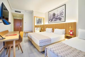 a hotel room with two beds and a desk at Exe Ciudad de Córdoba in Córdoba +17 photos