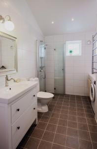 a white bathroom with a toilet and a sink at Small Red House In Central Vaxholm in Vaxholm