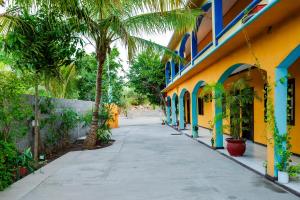 un trottoir à côté d'un bâtiment jaune avec des palmiers dans l'établissement OYO Hotel Miramar, Loreto, à Loreto