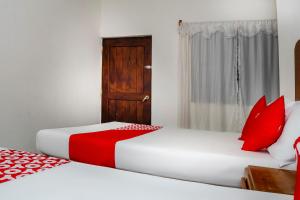 2 Betten mit roten Kissen in einem Zimmer in der Unterkunft OYO Hotel Miramar, Loreto in Loreto