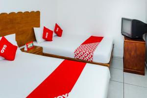 Cette chambre comprend 2 lits avec des oreillers rouges et une télévision. dans l'établissement OYO Hotel Miramar, Loreto, à Loreto
