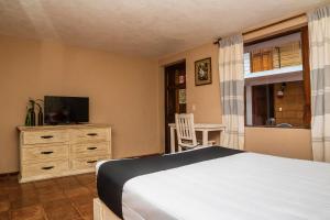 1 dormitorio con 1 cama y vestidor con TV en Hotel Rincon Soñado, Valle de Bravo en Valle de Bravo